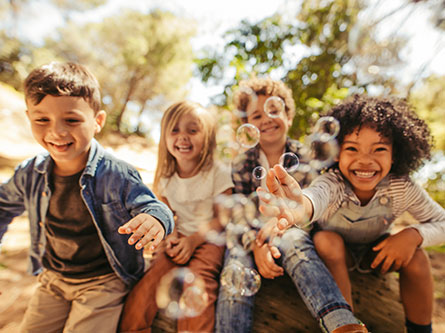 four kids playing with bubbles