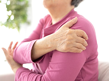 woman holding her shoulder with shoulder arthritis
