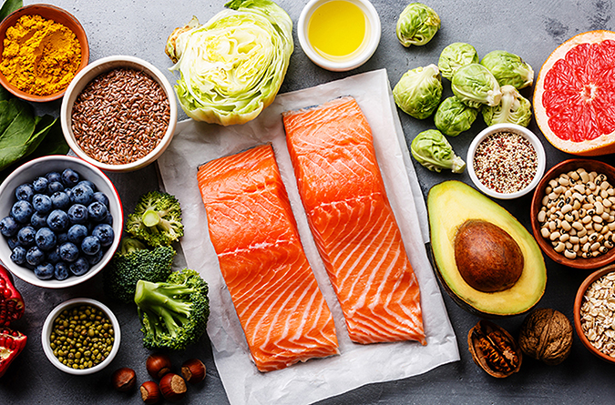 Table full of healthy foods, including salmon, berries, nuts, avocados and more